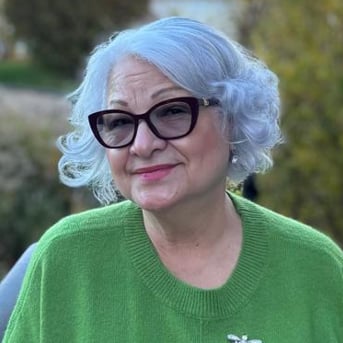 Pastora María del Pilar Rivera, del Concilio Internacional Visión en Acción, sonriendo al aire libre con un suéter verde
